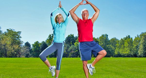 Älteres Paar beim Yoga auf einer Wiese