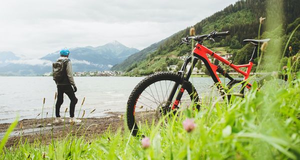 Mann, steht am Fluss, im Vordergrund sein Fahrrad.