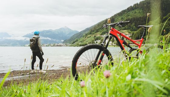 Mann, steht am Fluss, im Vordergrund sein Fahrrad.