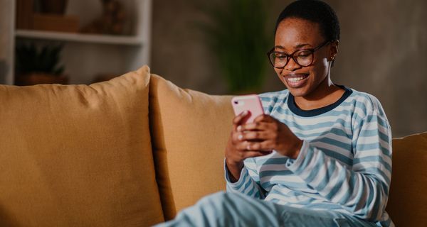 Frau, lächelt und schaut auf ihr Smartphone.