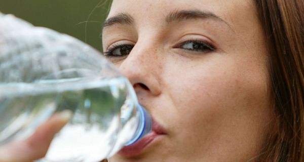 Junge Frau trinkt aus Wasserflasche.
