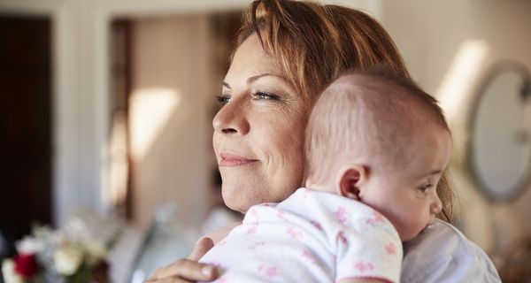 Frau, hält ein Baby auf dem Arm.