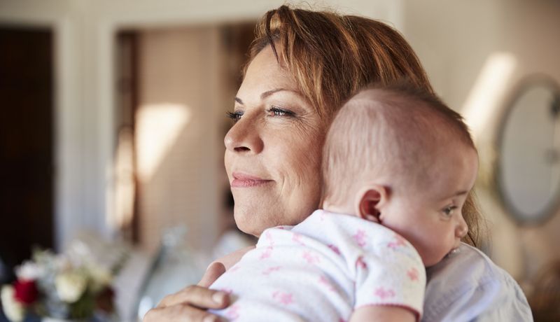 Frau, hält ein Baby auf dem Arm.