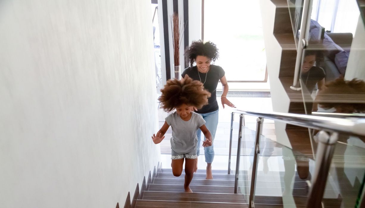 Mutter, rennt mit ihrer Tochter eine Treppe hoch.