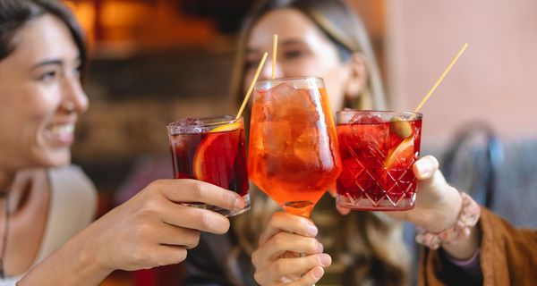 Frauen stoßen mit alkoholischen Getränken an.
