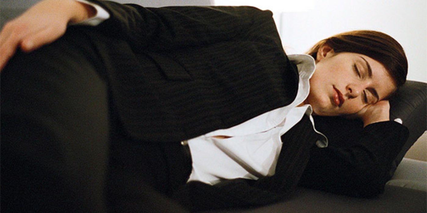 Junge Frau im Businessanzug (schwarz), weiße Bluse, beim Powernap auf einer Couch