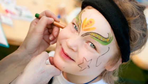 Kindergesicht wird für den Fasching geschminkt