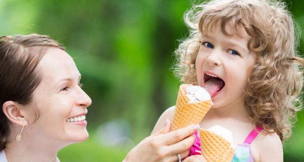 Mutter und Tochter an einem Sommertag, Mädchen isst eine Waffel mit Eis.
