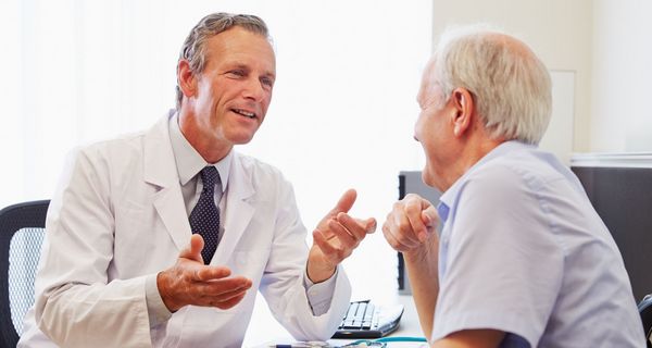 Arzt und Patient unterhalten sich. Sie wirken gutgelaunt.
