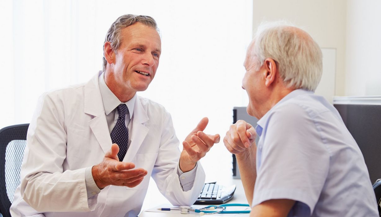Arzt und Patient unterhalten sich. Sie wirken gutgelaunt.