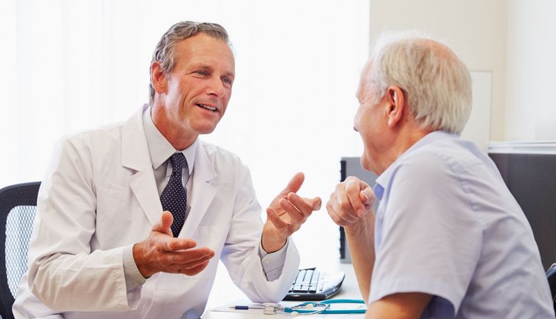Arzt und Patient unterhalten sich. Sie wirken gutgelaunt.