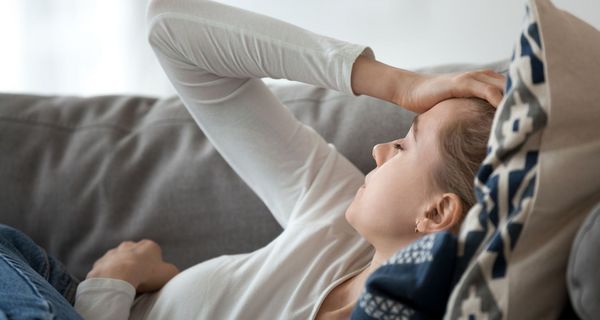 Frau, liegt erschöpft im Bett.