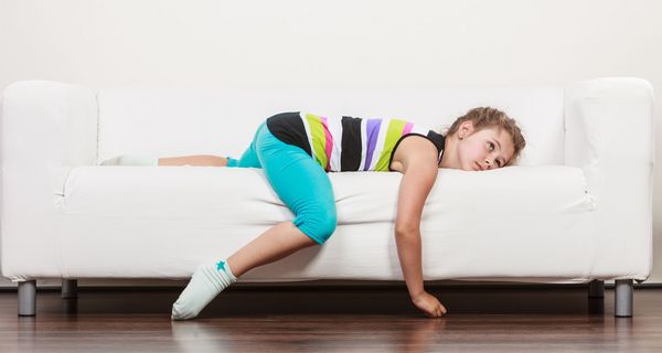 Mädchen, liegt gelangweilt und unruhig auf der Couch.