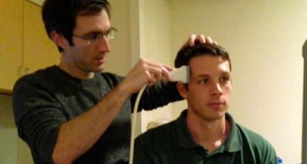 Studienleiter Jay Sanguinetti mit Ultraschallgerät am Kopf einer Testperson.
