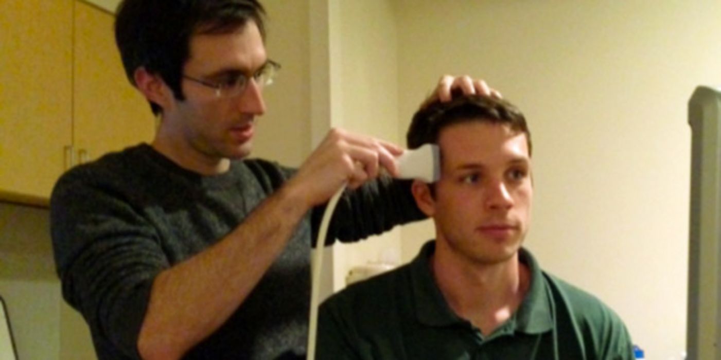 Studienleiter Jay Sanguinetti mit Ultraschallgerät am Kopf einer Testperson.