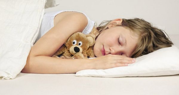 Schlafendes, ca. 10-jähriges Mädchen mit Kuscheltier im Arm
