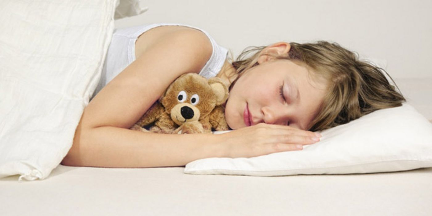Schlafendes, ca. 10-jähriges Mädchen mit Kuscheltier im Arm