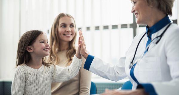 Mutter und Tochter bei Kinderärztin, Kind gibt Ärztin "High Five"