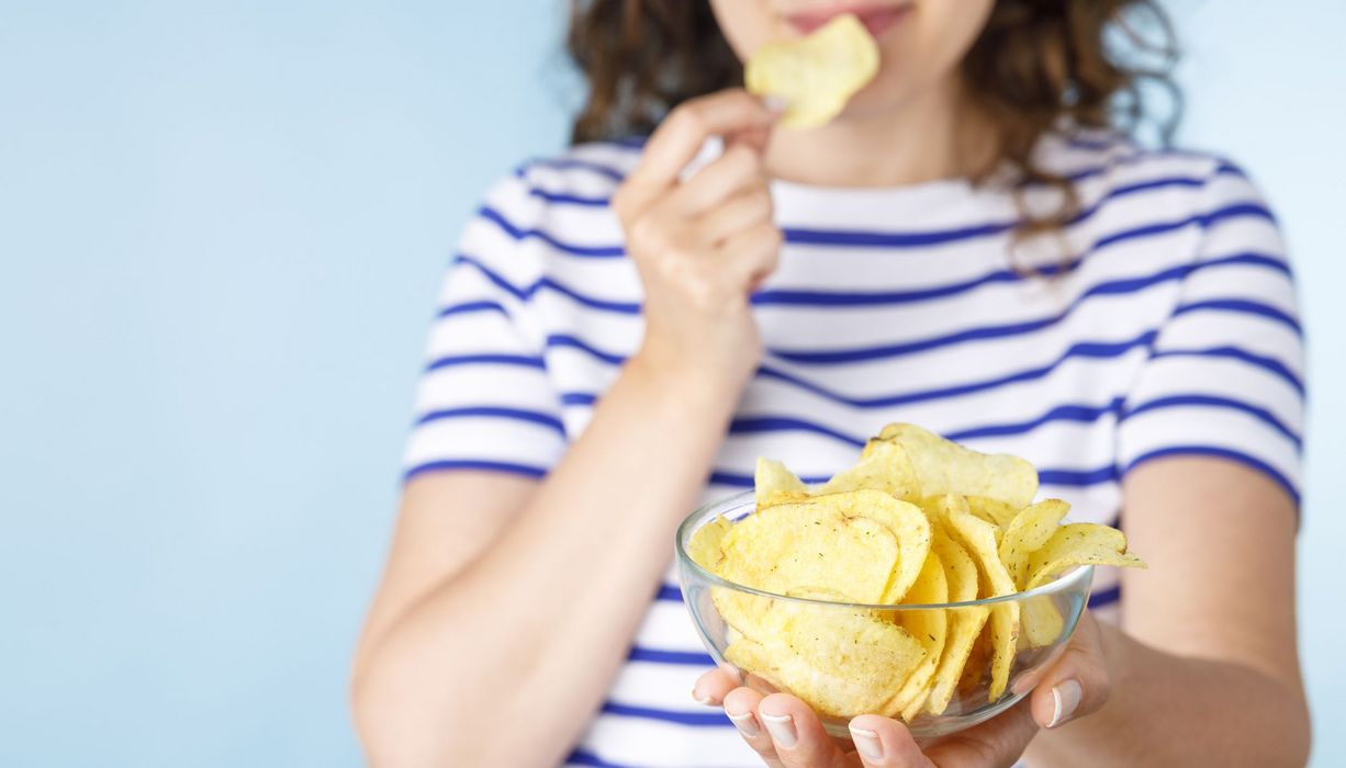 Frau, hält eine Schüssel mit Chips in die Kamera.