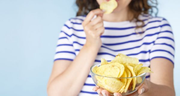 Frau, hält eine Schüssel mit Chips in die Kamera.