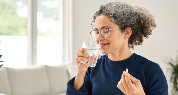 Frau nimmt Tablette ein.