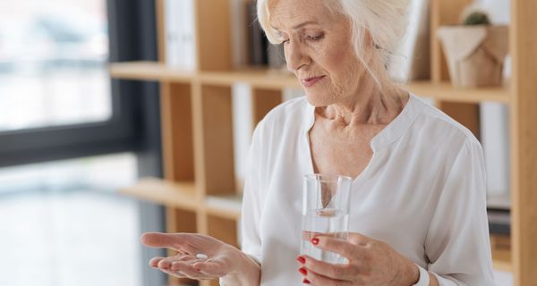Ältere Frau, ca. 65 Jahre alt, nimmt eine Tablette.