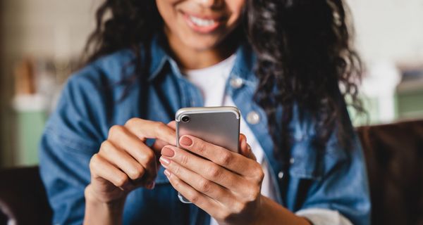 Junge Frau, tippt auf ihrem Smartphone.