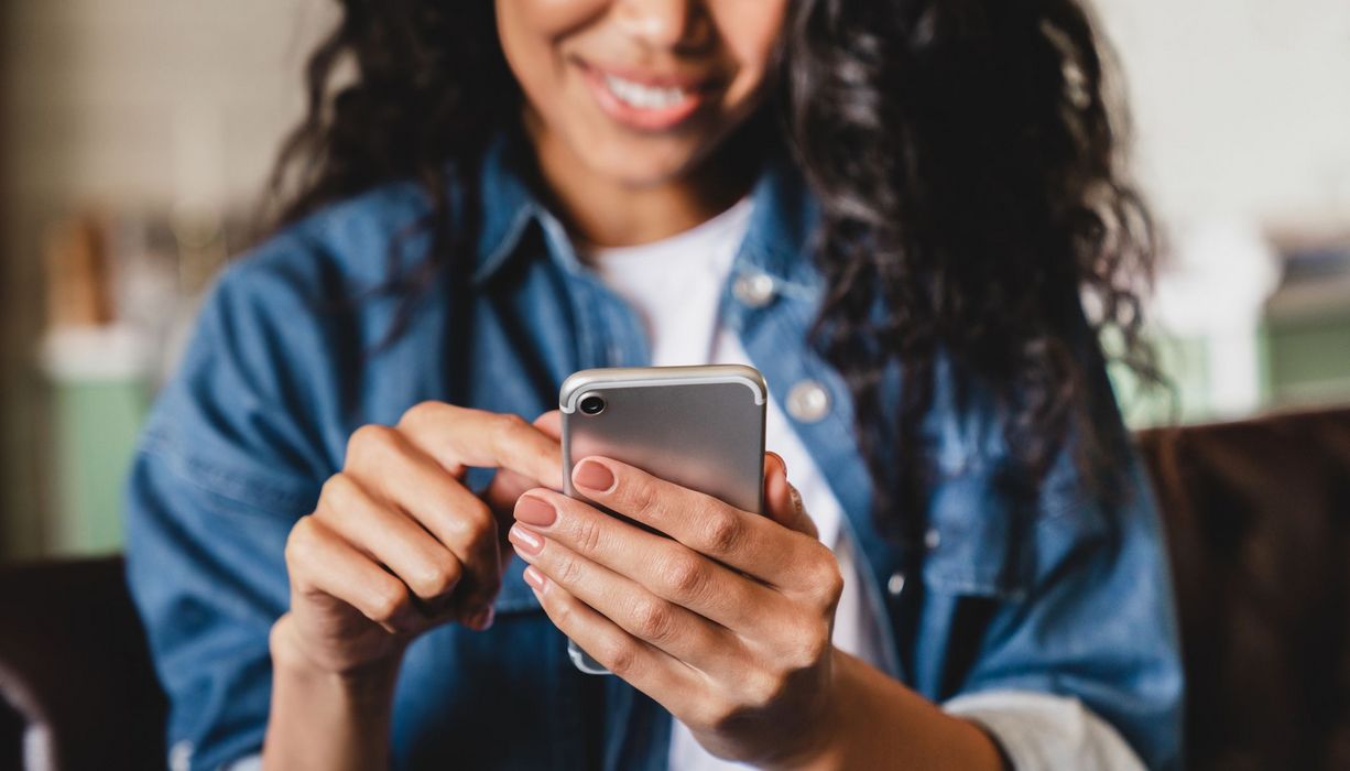 Junge Frau, tippt auf ihrem Smartphone.