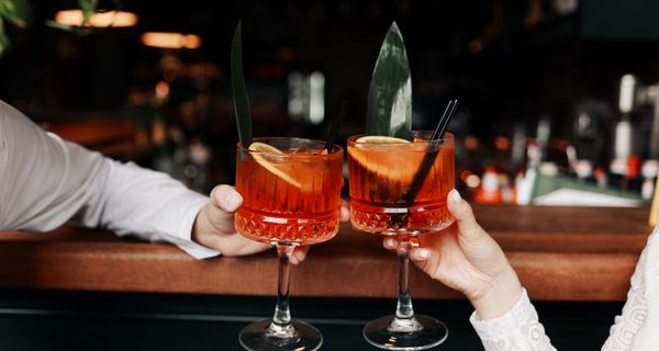 Mann und Frau, stoßen mit einem Cocktail an.