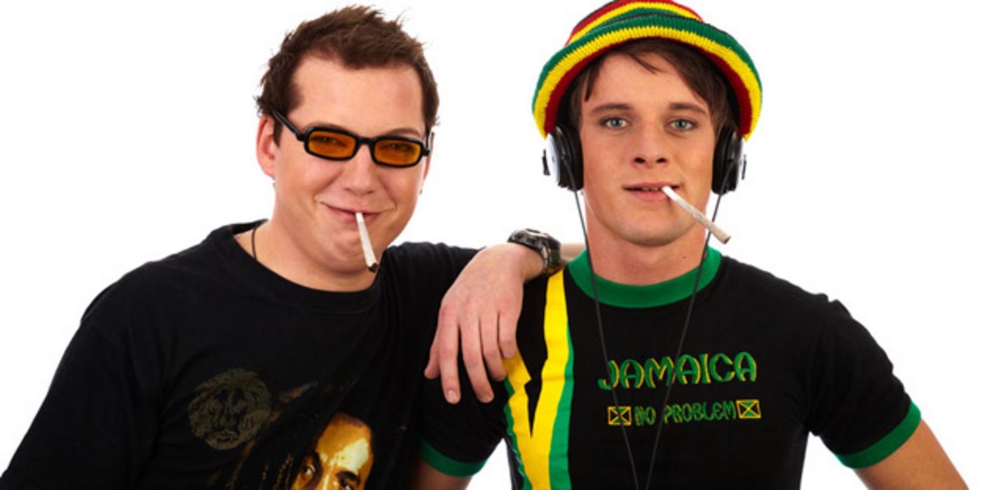 Zwei junge Männer im Reggae-Stil, die nebeneinander stehen und Cannabis rauchen.