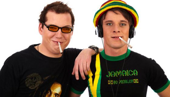 Zwei junge Männer im Reggae-Stil, die nebeneinander stehen und Cannabis rauchen.