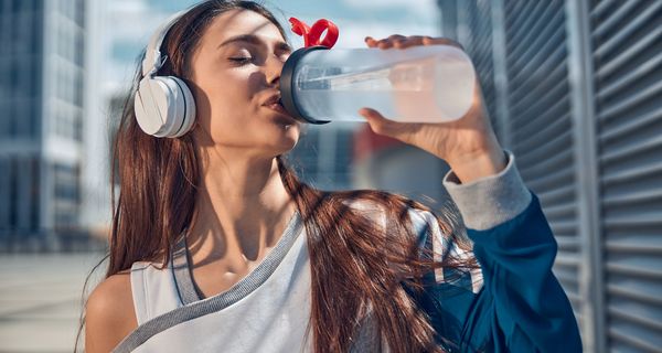 Junge Frau trinkt Wasser aus Plastikflasche