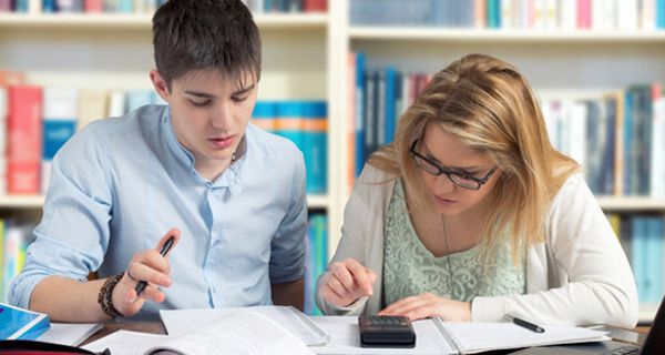 Teenager bei Mathe-Hausaufgaben vor Bücherwand