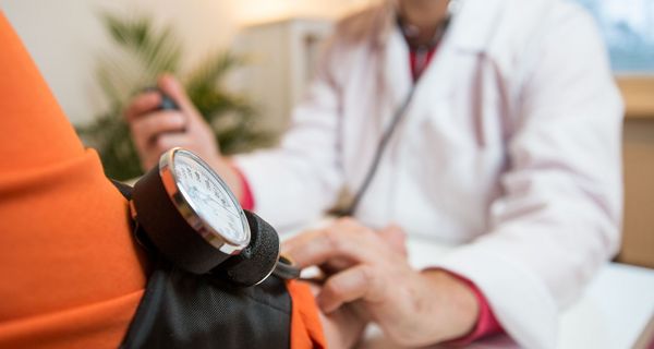 Arzt misst Blutdruck mit einer Oberarmmanschette.