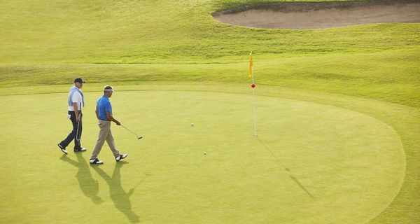 Zwei Männer, laufen über einen Golfplatz.