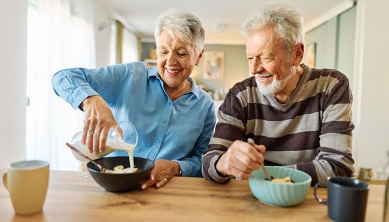 Seniorenpaar ist Müsli mit Milch.