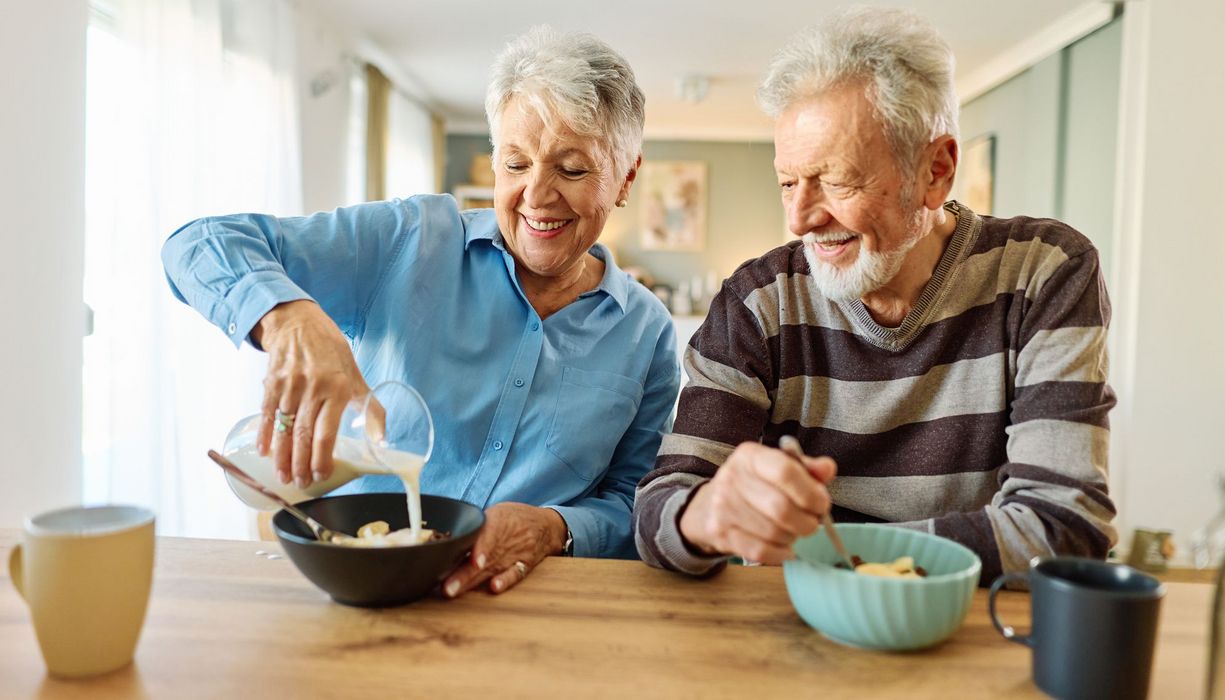 Seniorenpaar ist Müsli mit Milch.