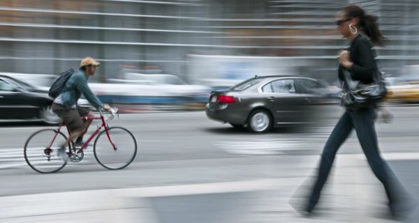 Straßenszene mit Auto, Fahrradfahrer und Fußgänger