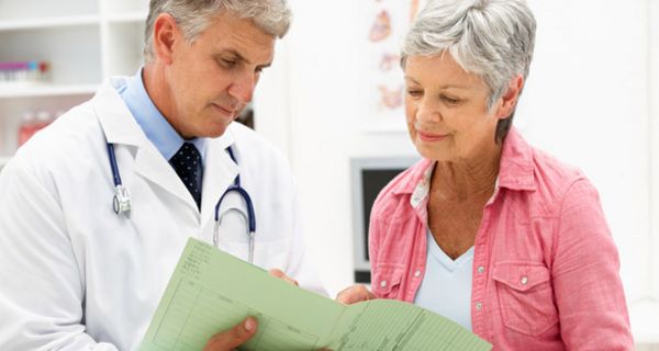 Arzt bespricht Krankenakte mit älterer Patientin