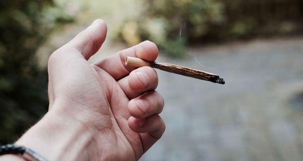 Mann, hält einen Joint in der Hand.