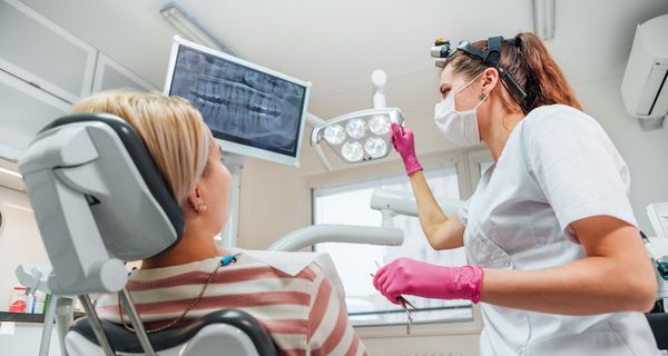 Zahnärztin und Patienten schauen sich eine Röntgenbild an.