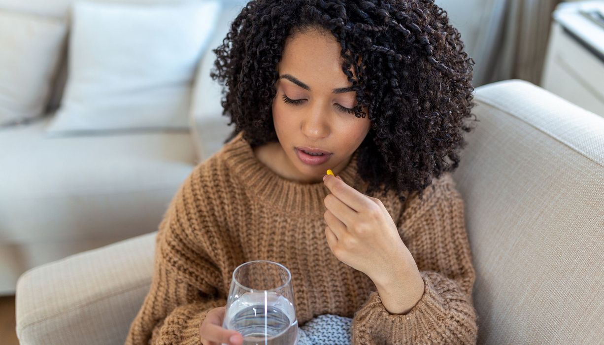 Junge Frau nimmt eine Tablette ein.