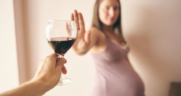 Schwangere Frau, lehnt ein Glas Wein ab.