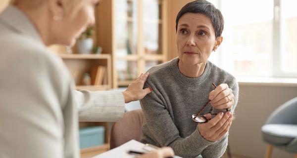 Ältere Frau mit kurzem Haar, hört einer Psychotherapeuten zu.