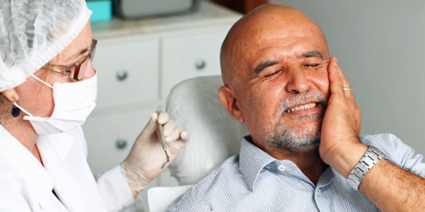 Mann mit Zahnschmerzen auf dem Behandlungsstuhl beim Arzt