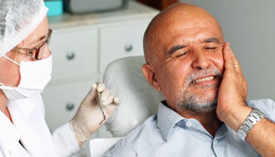 Mann mit Zahnschmerzen auf dem Behandlungsstuhl beim Arzt