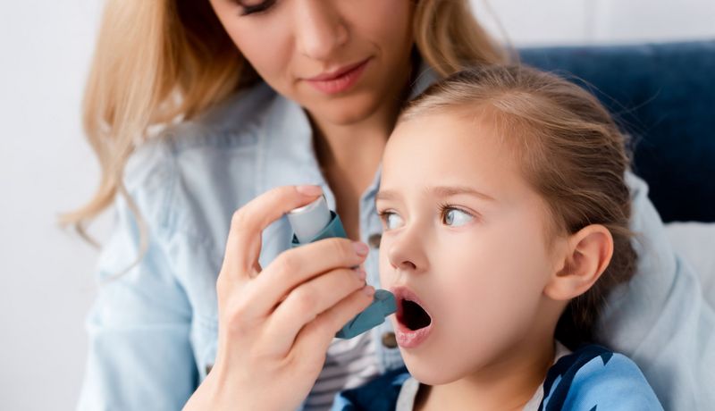 Mutter, verabreicht ihrem Kind Asthmaspray.