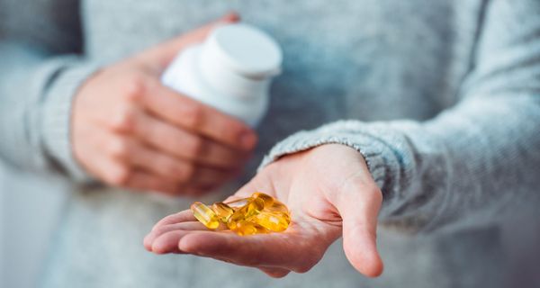 Frau, hält eine Dose in der einen Hand und Tabletten in der anderen Hand.