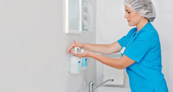 Klinikmitarbeiterin reinigt sich vor einer OP die Hände