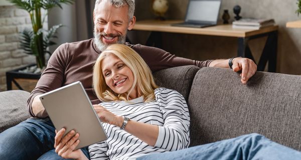 Frau und Mann, ca. 55 Jahre alt, liegen zusammen auf der Couch.